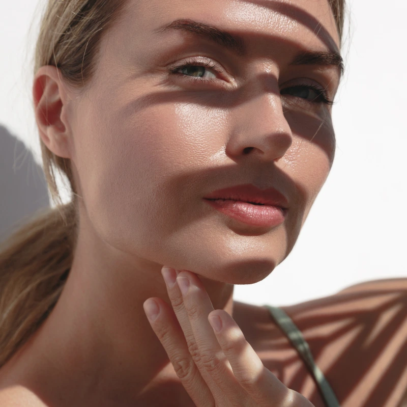 Woman touching her chin and jawline in profile, demonstrating chin and neck contour